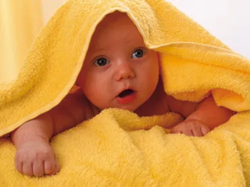 Ein Baby unter einem gelben Handtuch