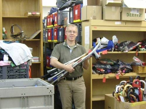 Ein Mitarbeiter des Fundbüros mit Gehhilfen, Regenschirmen und anderen Fundstücken