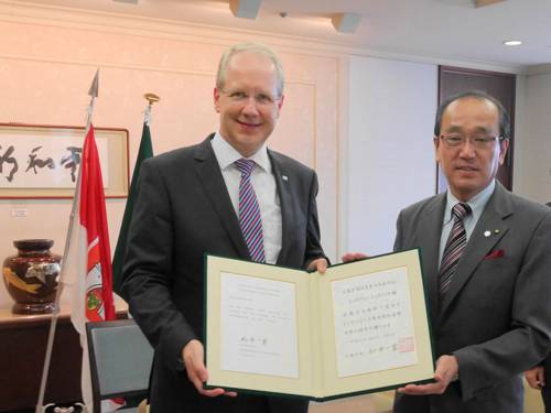 Oberbürgermeister Stefan Schostok und Bürgermeister Kazumi Matsui halten eine Urkunde