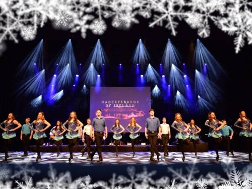 Tänzer und Tänzerinnen stehen auf einer Bühne. Sie tragen blaue Kostüme.