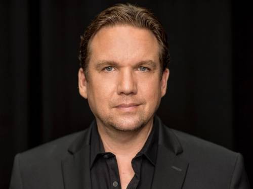 Porträt eines Mannes mit kurzem Haar und Dreitagebart in Hemd und Sakko