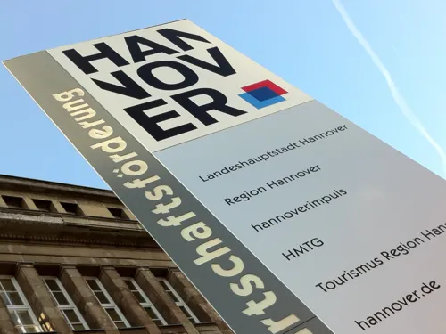 Gebäude, vor dem eine Säule mit Schriftzügen steht