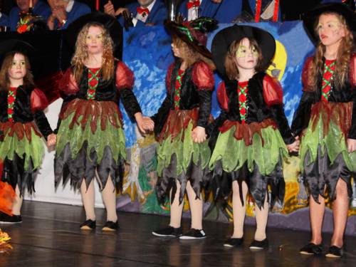 Als Hexen verkleidete kleine Mädchen stehen in einer Reihe auf einer Bühne