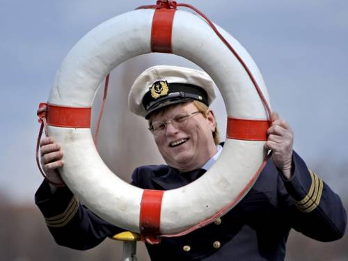 Kapitän mit Rettungsring vor dem Gesicht