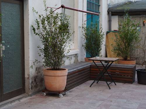 Eine Hofecke mit einem Tisch, einer Bank und vier großen Kübelpflanzen.