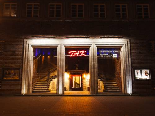 Ein hell erleuchtetes, dreigeteiltes Portal in einer dunklen Hausfassade.