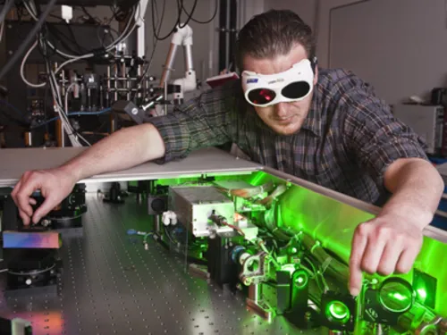 Ein Mann mit Schutzbrille führt ein physikalisches Experiment durch.