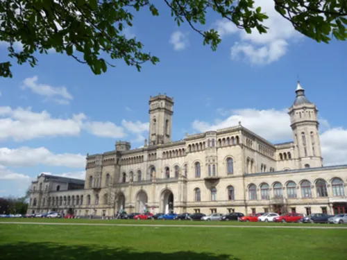 Vor einem schloss&auml;hnlichen Geb&auml;ude parken mehrere Autos.