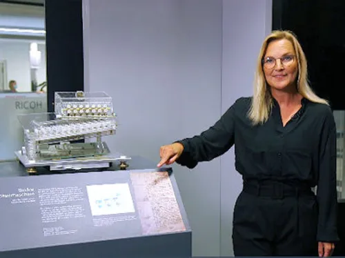Frau zeigt auf ein Exponat in einer Ausstellung