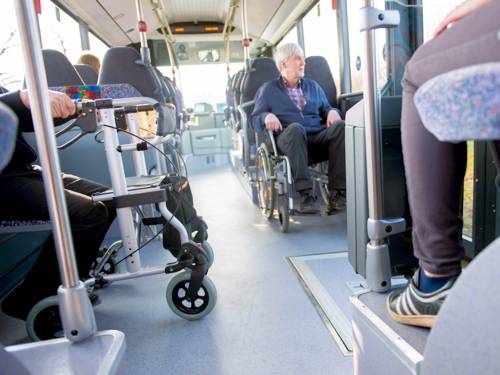 Mann in Rollstuhl und Rollator in Bus