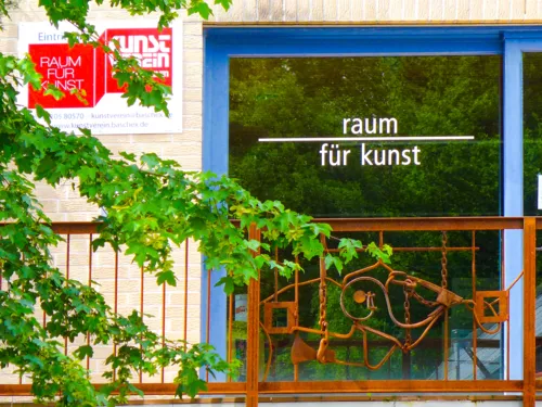 Gläserne Eingangstür mit dem Schriftzug Raum für Kunst.