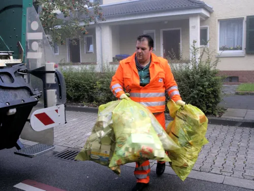 Mann in oranger Kleidung mit Gelben Säcken