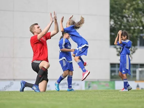 Ein Mann und drei Mädchen in Fußballtrikots