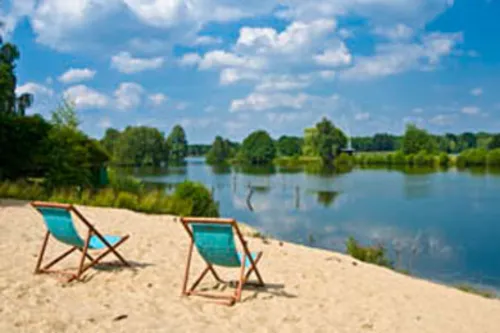 Zwei Sonnenliegen am Strand ausgerichtet mit Blick auf das Wasser.