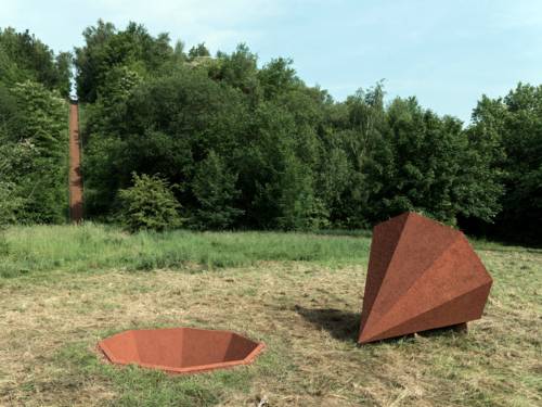 Aus dem grasbewachsenen Boden scheint ein achteckiger Kegel ausgestochen zu sein, der neben dem Loch liegt.