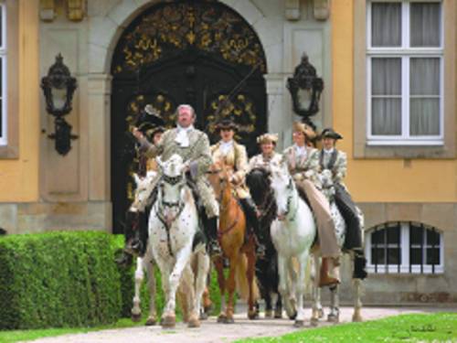 Menschen in Uniformen reiten auf Pferden.