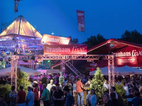 Festzelt und Eventbereich voller Menschen am Abend.
