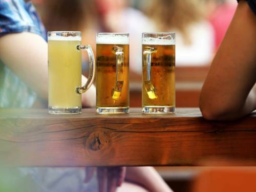 Drei Gläser Bier auf einem Holzbalken. 
