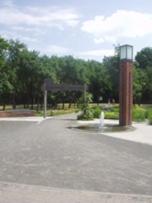 Weg mit gemauerter Lichtstele und einem Holzbogen mit Aufschrift "Stadtpark Garbsen"