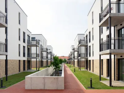 Blick entlang einer Baumpflanzung durch ein Wohnviertel mit einigen modernen Wohngeb&auml;uden.