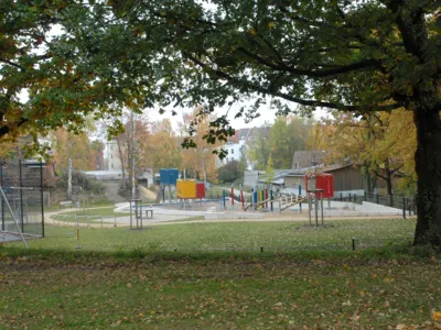 Spielplatz, im Bildvordergrund Gr&uuml;nfl&auml;che mit B&auml;umen
