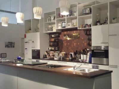 Eine Küche mit Kochinsel. Die vier Lampen an der Decke sehen aus wie Kochmützen. In der Mitte des Bildes ist ein Abspielsymbol abgebildet. 