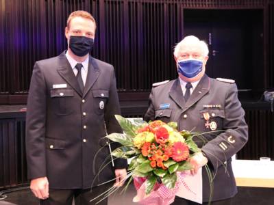 Blumen und Ehrennadel zum Dank: Martin Voß (links) überreicht Eberhard Schmidt das Feuerwehrehrenzeichen am Bande. 