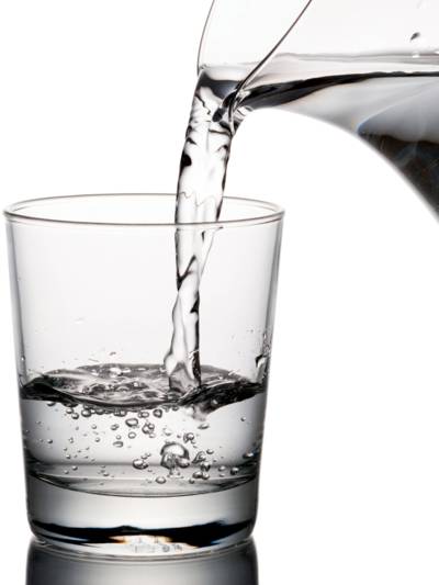 Wasser läuft aus einer Karaffe in ein Trinkglas.