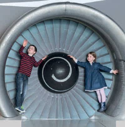 Zwei Kinder vor einer Flugzeugturbine.