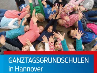 Kinder liegen im Kreis auf dem Boden und strecken ihre Arme dem Betrachter entgegen