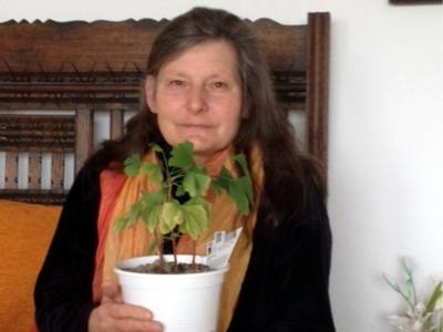 Frau Cornelia Mohrig hält ein Topf mit einer Gingko-Pflanze in der Hand.