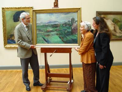 In einem Museumsraum stehen neben einem ausgestellten Gemälde, das eine italienische Landschaft zeigt, drei Personen: links der ehemalige Kulturdezernent Böhlmann, rechts davon eine ältere Dame und eine Frau mittleren Alters.