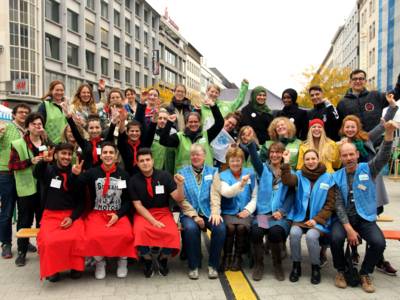 Eine gro&szlig;e Gruppe, die in der Innenstadt f&uuml;r ein Foto in die Kamera l&auml;chelt. 