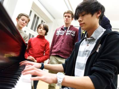 Junge Menschen beim Klavierunterricht. 
