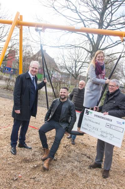 Vier Männer und eine Frau auf und neben einer Schaukel. 