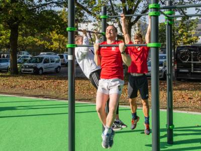 Drei Menschen an Sportstangen. 