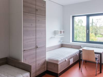 Ein Raum mit zwei Betten und einem Schrank, einem Tisch und einem Stuhl