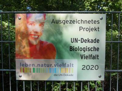 Ein Schild, auf dem steht "Ausgezeichnetes Projekt UN-Dekade Biologische Vielfalt"