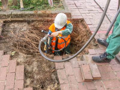 Mann mit einem Saugger&auml;t zwischen Wurzeln in der Erde. 