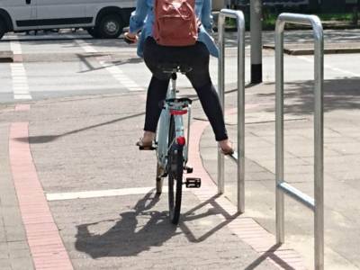 Fahrradfahrerin, die ihr Bein auf einer Trittstange abstellt.