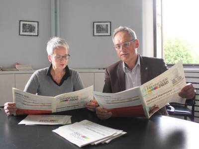 Zwei Personen lesen die aktuelle Ausgabe der Projektzeitung zu "Mein Hannover 2030"