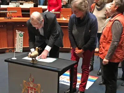 Auf einem Tisch im Hodlersaal, der mit einer Mayors-for-Peace-Fahne versehen ist, unterzeichnet der Oberb&uuml;rgermeister ein Dokument.