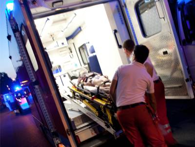 Rettungsassistenten befestigen die Trage mit Patient auf dem Tragentisch eines RTW