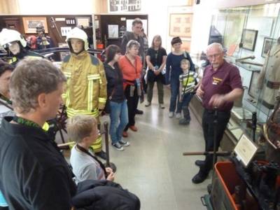 Die Besuchergruppe hört den Erklärungen von Alfred Falkenberg gespannt zu und bestaunt auch den neuen sandfabrenen Feuerwehrschutzanzug.