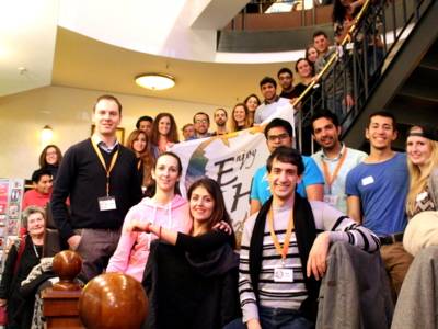 Etwa 25 Leute stehen in einer Reihe und eine geschwungene Treppe aufw&auml;rts im Mister Q. und halten ein Transparent vor sich mit dem Aufdruck "Enjoy Hannover"