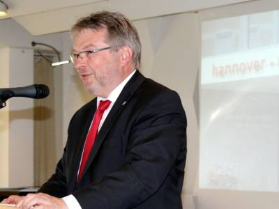 Ein Mann steht hinter einem Pult und spricht.