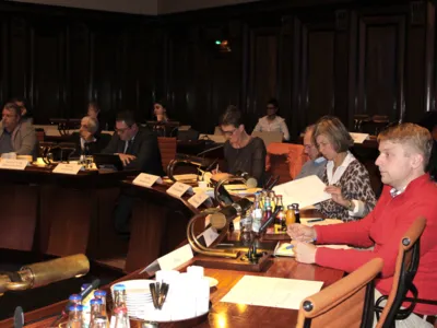 Elf Personen sitzen im Hodlersaal hinter Pulten, oder in Sitzreihen dahinter. Einige davon schauen auf Unterlagen, die vor ihnen liegen, andere blicken nach vorn.
