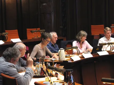 Sechs Personen - zwei Frauen und vier M&auml;nner - sitzen im Hodlersaal des Neuen Rathauses an Pulten.