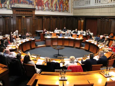 Blick in den Hodlersaal. Etwa 25 Personen sitzen hinter Pulten.