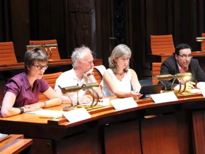 Vier Personen - zwei Frauen und zwei M&auml;nner - sitzen im Hodlersaal hinter Pulten. Die Frau links spricht in ein am Tisch befestigtes Mikrofon.